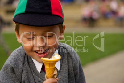 Close-up of smiling uniformed schoolboy eating ice-cream