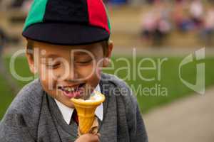 Close-up of smiling uniformed schoolboy eating ice-cream