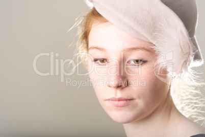 Close-up of thoughtful redhead in taupe hat