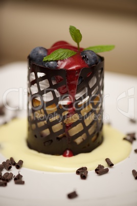 Cylindrical cheesecake in chocolate basket with blueberries