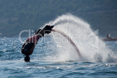 Flyboarder about to dive into backlit waves