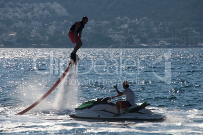 Flyboarder crouching above man on Jet Ski