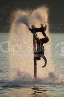 Flyboarder diving amid spray after back flip