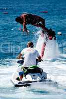 Flyboarder diving behind man on Jet Ski