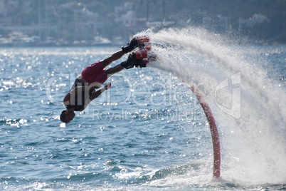 Flyboarder diving followed by arc of spray