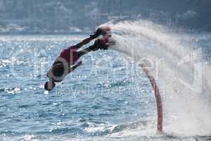Flyboarder diving followed by arc of spray