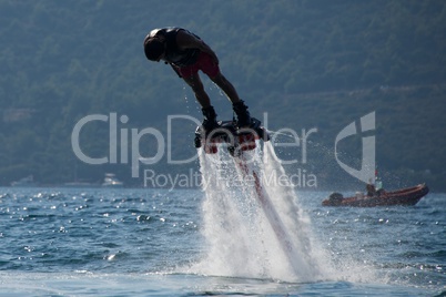Flyboarder diving headfirst with inflatable in background