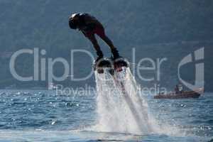 Flyboarder diving headfirst with inflatable in background