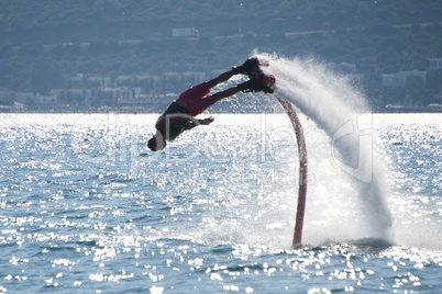 Flyboarder diving headfirst leaving arc of spray