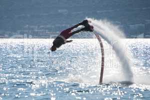 Flyboarder diving headfirst leaving arc of spray