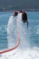 Flyboarder diving into water followed by hose
