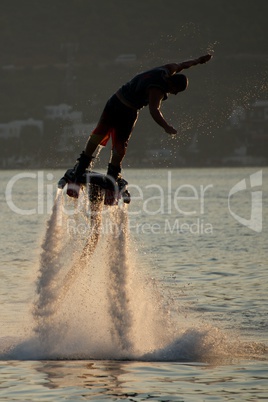 Flyboarder dripping with spray backlit before dive