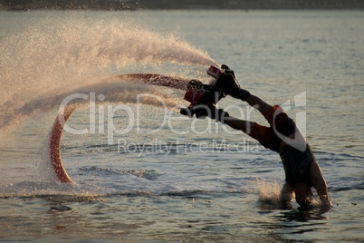 Flyboarder entering water leaving trail of spray