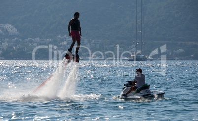 Flyboarder flying beside Jet Ski and yacht