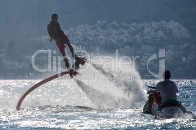 Flyboarder flying beside man on Jet Ski