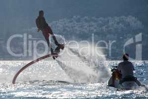 Flyboarder flying beside man on Jet Ski