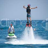 Flyboarder giving thumbs up beside jet ski