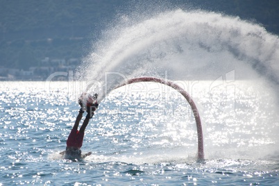 Flyboarder falling over backwards into backlit waves