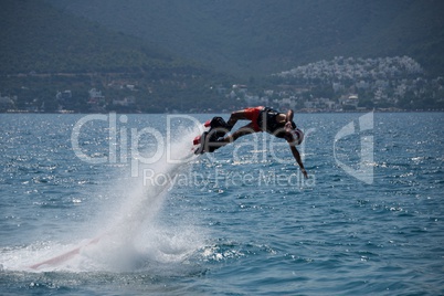 Flyboarder in helmet diving horizontal into sea