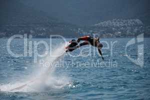 Flyboarder in helmet diving horizontal into sea