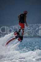 Flyboarder in helmet flying above bubbling whitewater