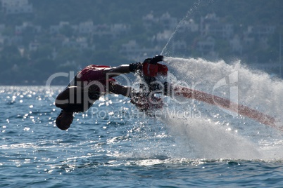 Flyboarder in low dive into backlit waves