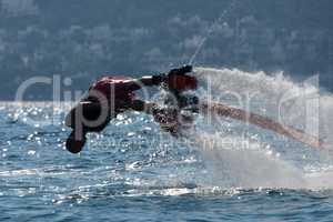 Flyboarder in low dive into backlit waves