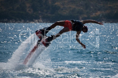 Flyboarder in pink shorts cartwheeling into waves