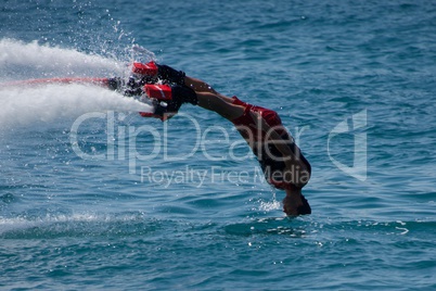Flyboarder in red diving headfirst into sea