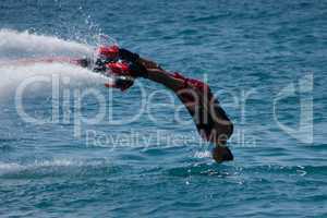 Flyboarder in red diving headfirst into sea