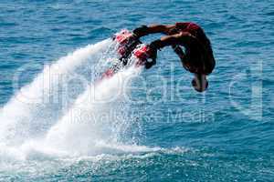 Flyboarder in red diving headfirst into water