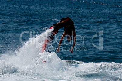 Flyboarder in red diving headfirst into whitewater