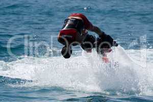 Flyboarder in red diving headfirst towards camera