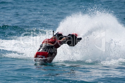 Flyboarder in red entering water towards camera