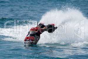 Flyboarder in red entering water towards camera