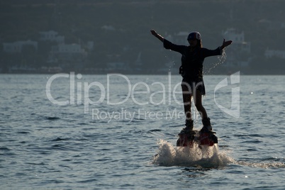 Flyboarder with arms out just above water