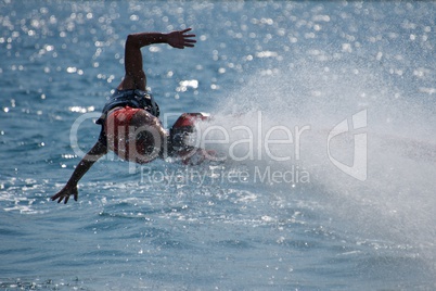 Flyboarder with outstretched arms low over water
