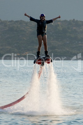 Flyboarder with thumbs up high above water