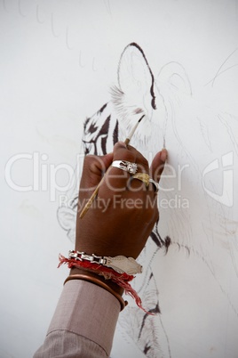 Hand of artist painting tiger