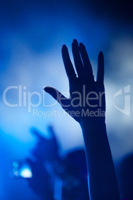 Hand of fan silhouetted against blue smoke