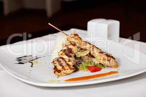 Lamb kebab on white plate with cruet