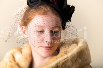 Redhead in black veiled hat and fur coat looking down