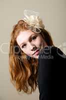 Redhead in cream fascinator looking over shoulder