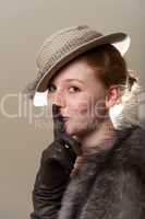 Redhead in hat putting finger to lips