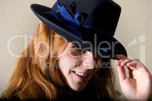 Redhead smiling in black hat touching brim