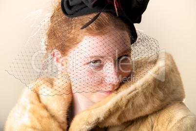 Redhead smiling shyly in black veiled hat and fur coat