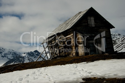 Rickety hut on ridge with mountains behind