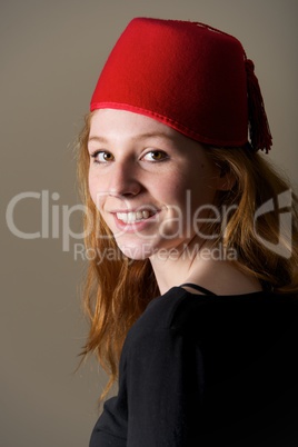 Smiling redhead in fez looking over shoulder