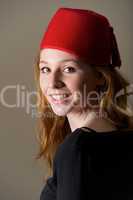 Smiling redhead in fez looking over shoulder