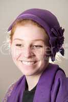 Smiling redhead in purple hat biting lip